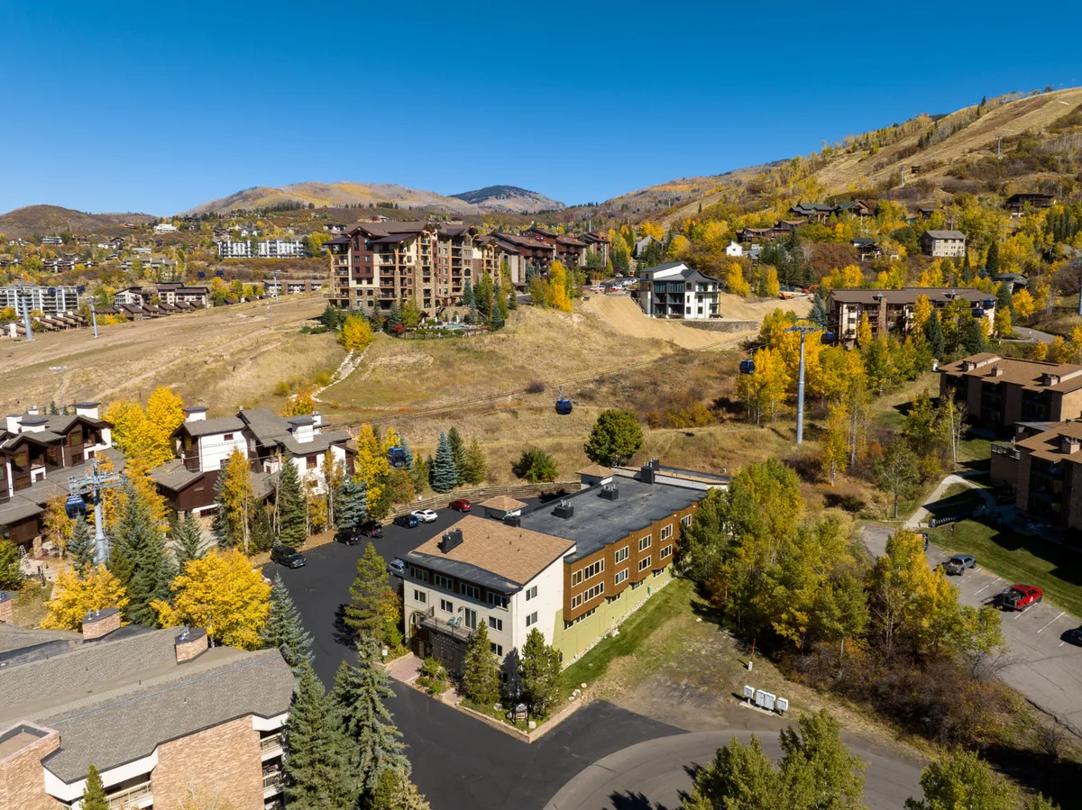A tranquil neighborhood scene showcases Steamboat’s mountains rising above a tapestry of autumn foliage and inviting buildings, promising scenic strolls and vibrant seasonal colors just beyond your door.
